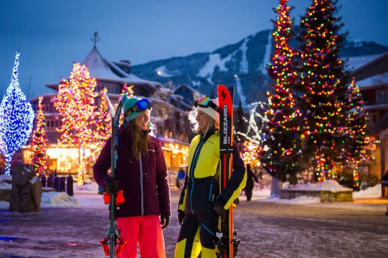 Twee wintersporters op het met kerstverlichting versierde plein van Whistler, Canada