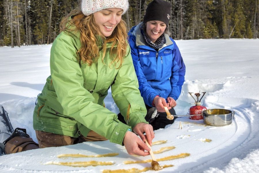 Wandelaars maken maple taffy tijdens een sneeuwschoenwandeling in Kootenay National Park in Canada