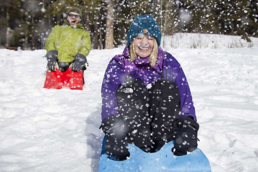 Twee wandelaars gaat op sledes van een heuvel tijdens een sneeuwschoenwandeling in Canada