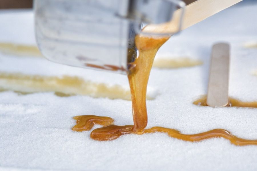 Hot maple taffy wordt op sneeuw gegoten tijdens een sneeuwschoenwandeling in Canada