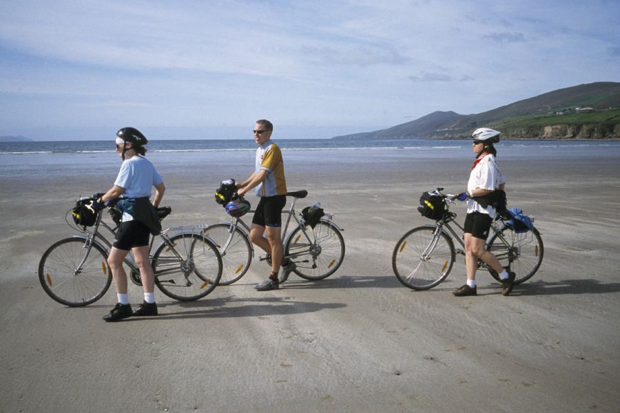 Drie fietsers op het strand met de fiets aan de hand in Kerry