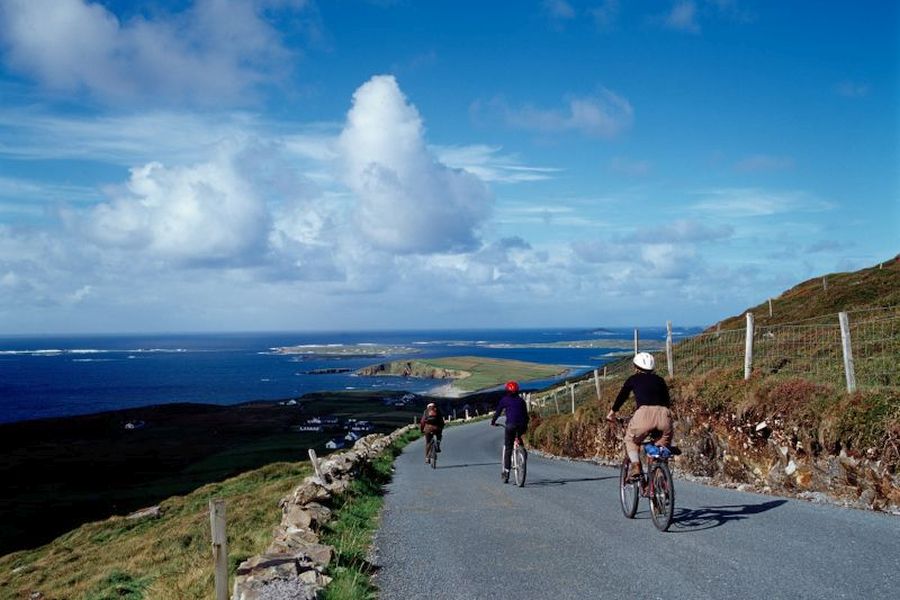 Drie fietsers gaan een heuvel af bij de kust